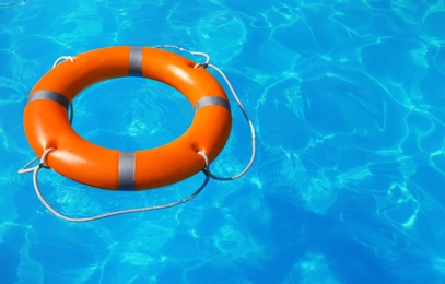 Photo of Lifebuoy floating in swimming pool on sunny day. Space for text