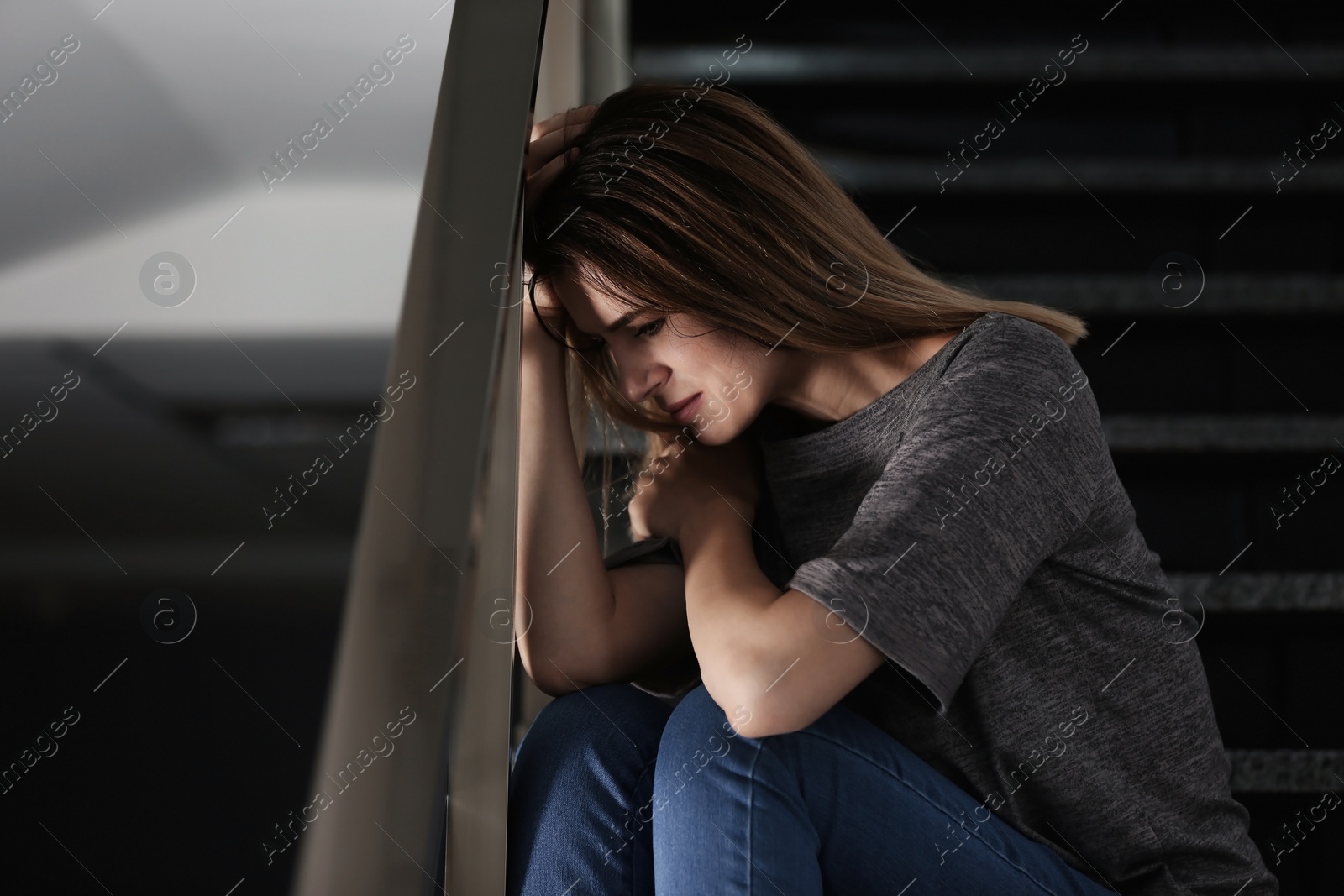 Photo of Lonely depressed woman sitting on stairs indoors