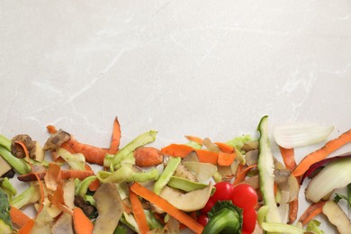 Photo of Peels of fresh vegetables on light grey marble table, flat lay. Space for text