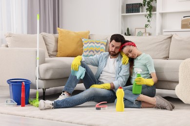 Photo of Spring cleaning. Tired couple with detergents and mop in living room