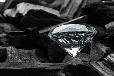 Photo of Beautiful shiny diamond on coal, closeup view