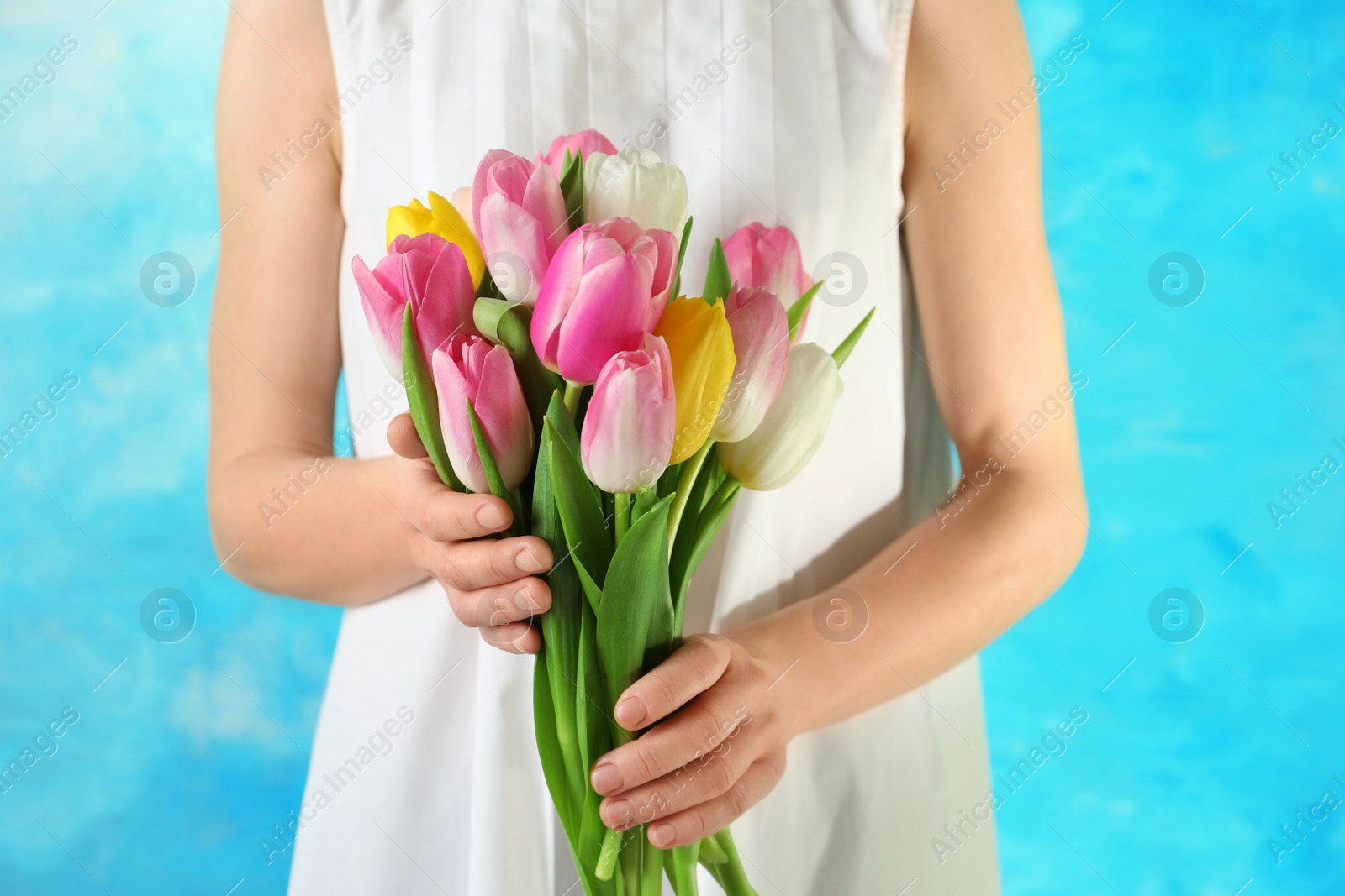 Photo of Girl holding bouquet of beautiful spring tulips on color background, closeup. International Women's Day