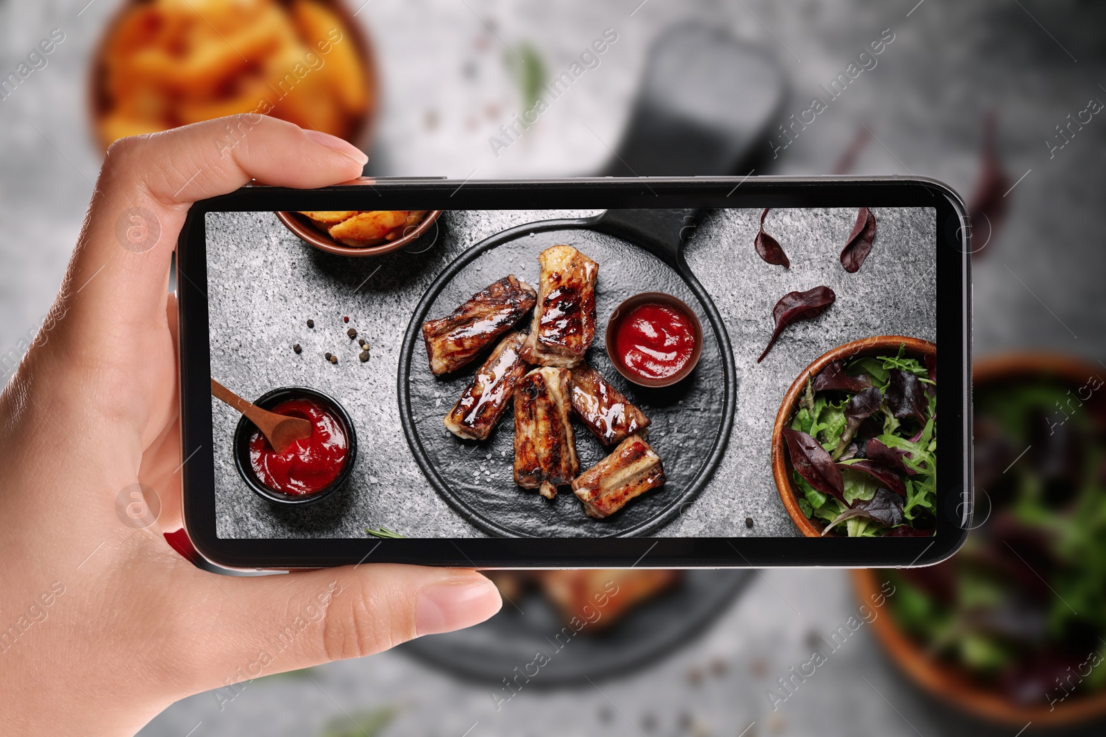 Image of Blogger taking picture of delicious grilled ribs at table, closeup. Food photography