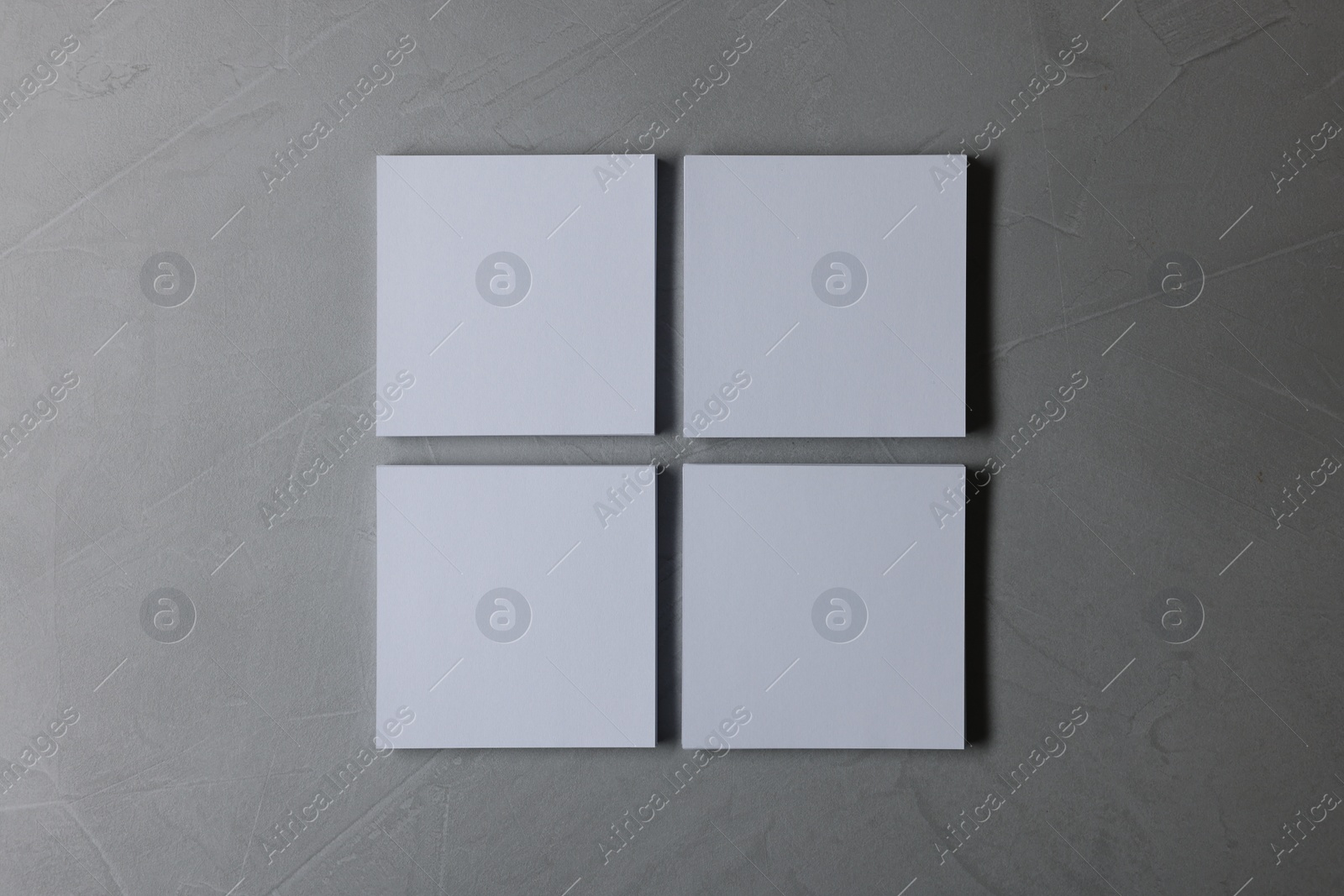 Photo of Blank paper sheets on grey textured background, top view. Mockup for design