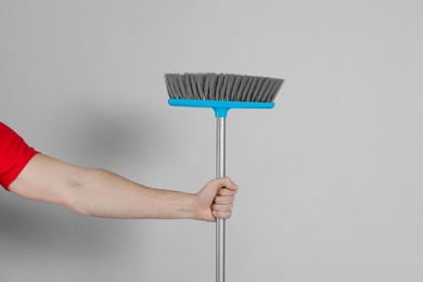 Man with broom on grey background, closeup
