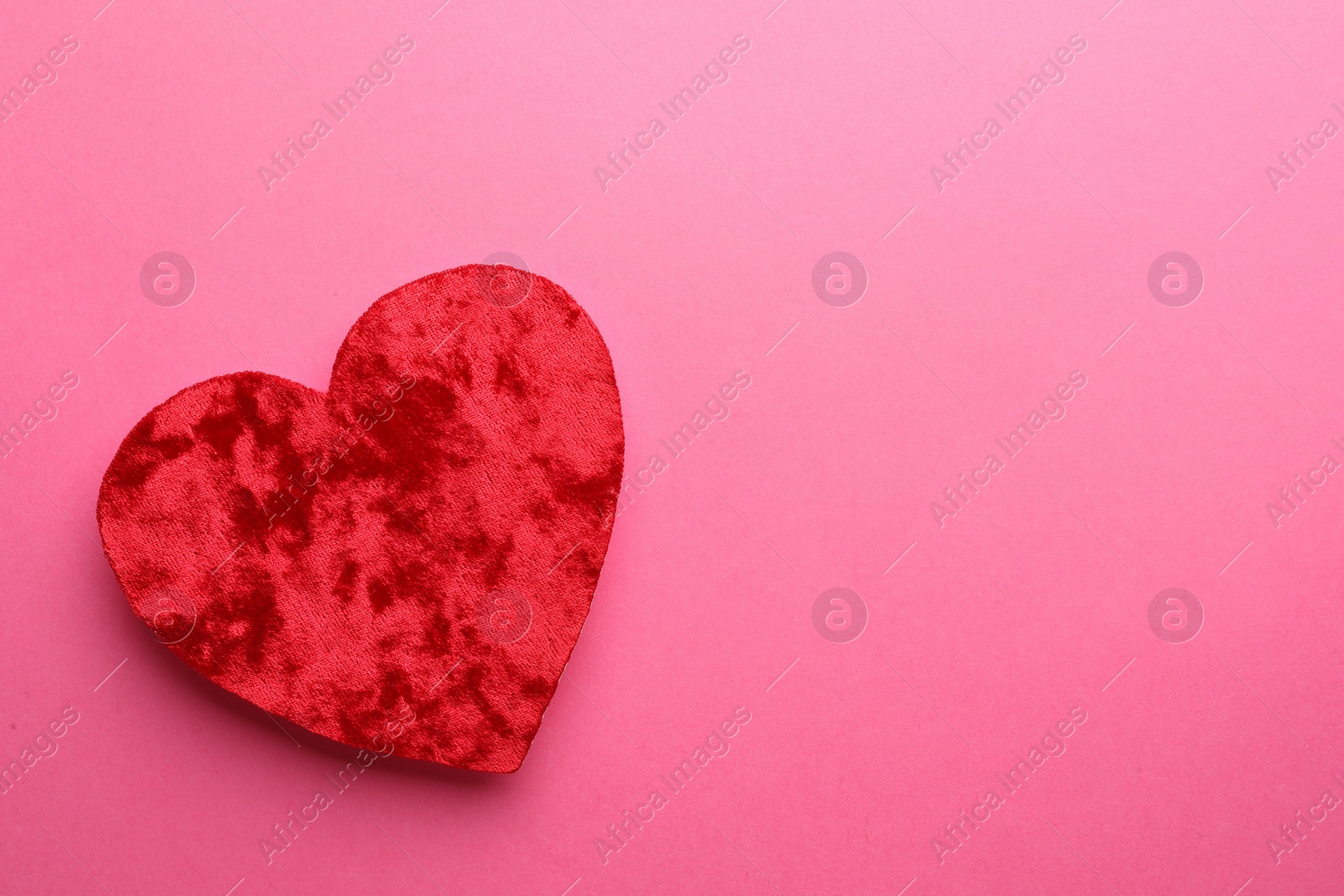 Photo of Red textile heart on pink background, top view. Space for text