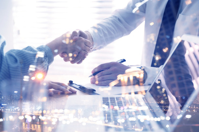 Business people shaking hands and night cityscape, closeup. Multiple exposure 