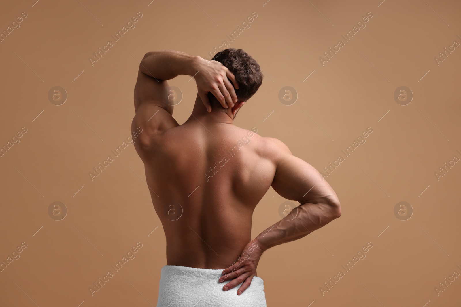 Photo of Man suffering from back and neck pain on beige background, back view