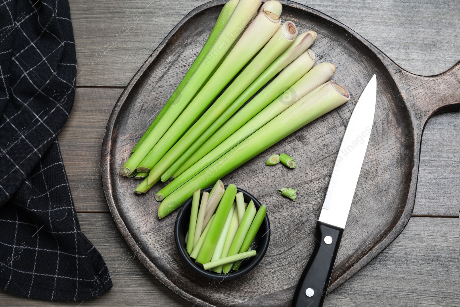 Photo of Fresh lemongrass, knife and cutting board on wooden table, flat lay