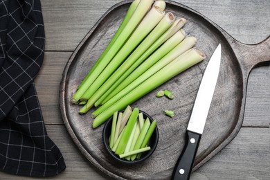 Fresh lemongrass, knife and cutting board on wooden table, flat lay