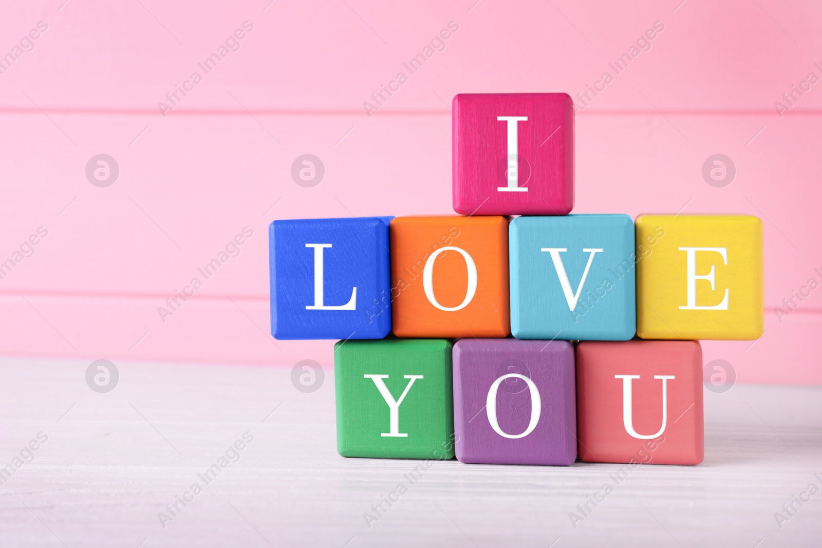 Photo of Phrase I love You made of color cubes on pink background