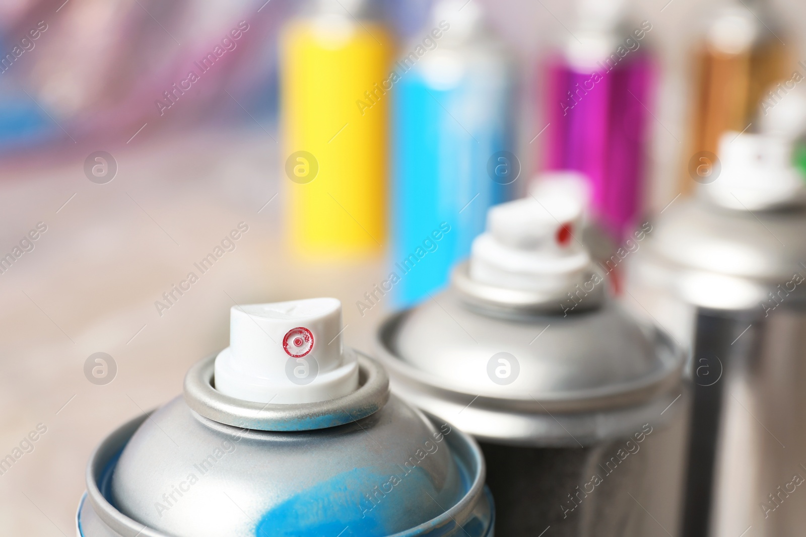 Photo of Used cans of spray paint on blurred background, closeup view