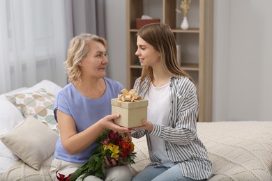 Young daughter congratulating her mom with gift at home. Happy Mother's Day