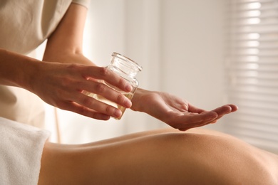 Photo of Young woman receiving back massage with oil in spa salon, closeup