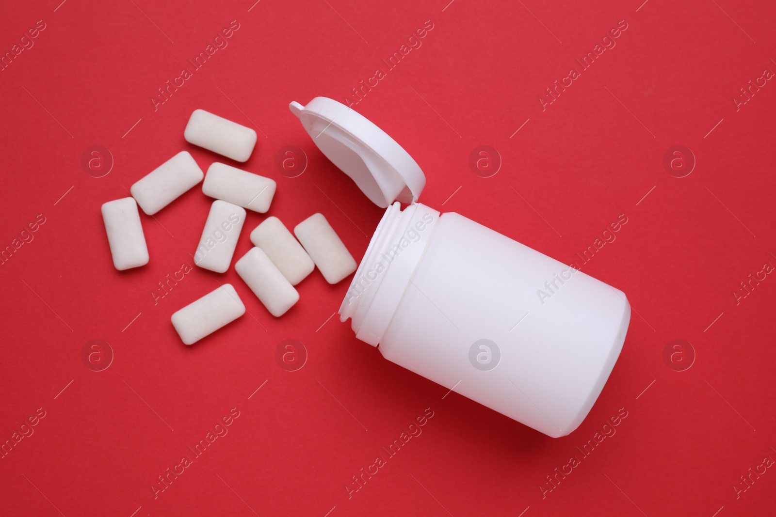 Photo of Jar with chewing gums on red background, flat lay