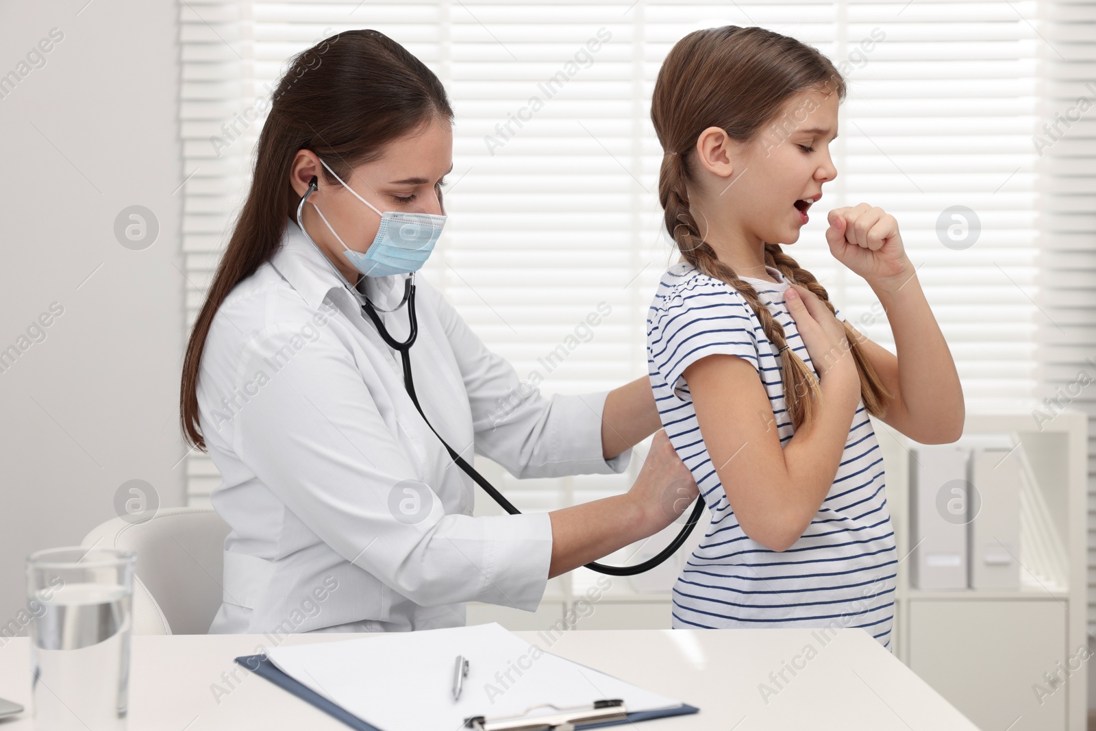 Photo of Doctor examining coughing girl in hospital. Cold symptoms