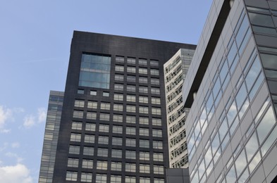 Exterior of beautiful modern skyscraper against blue sky, low angle view