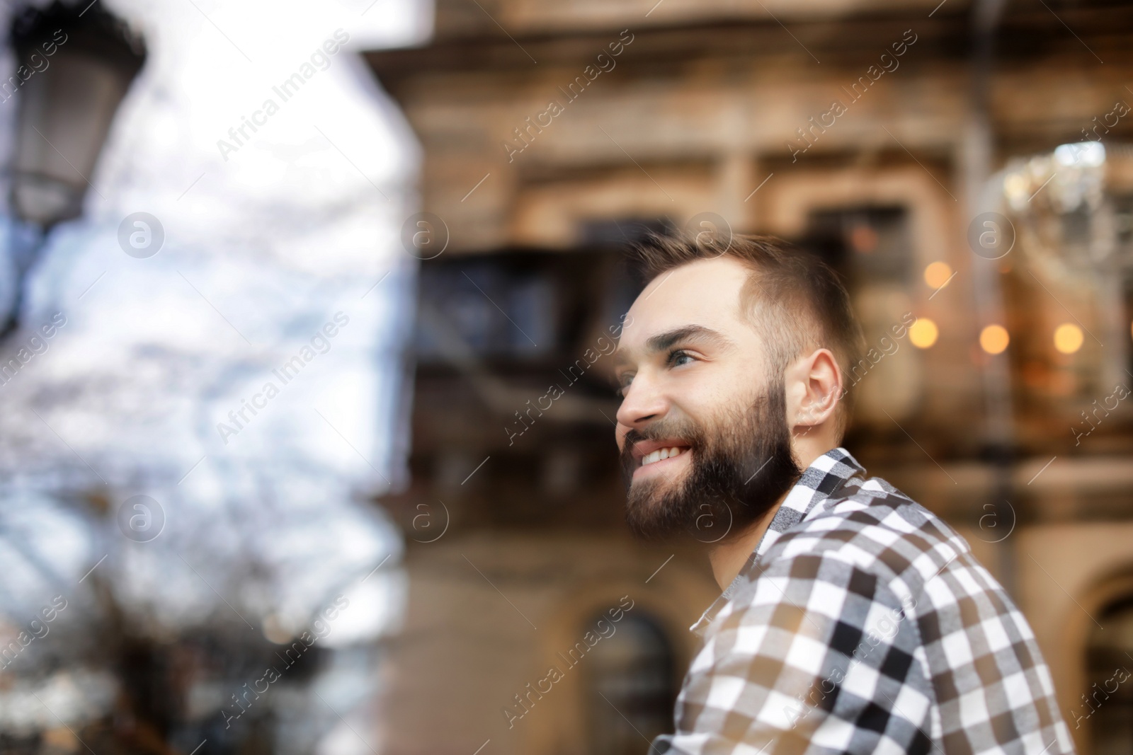 Photo of Handsome young man sitting in cafe, view from outdoors through window