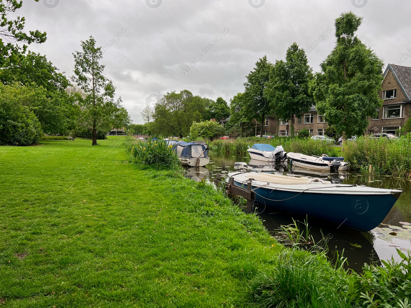 Photo of Beautiful view of green lawn near city canal with different boats