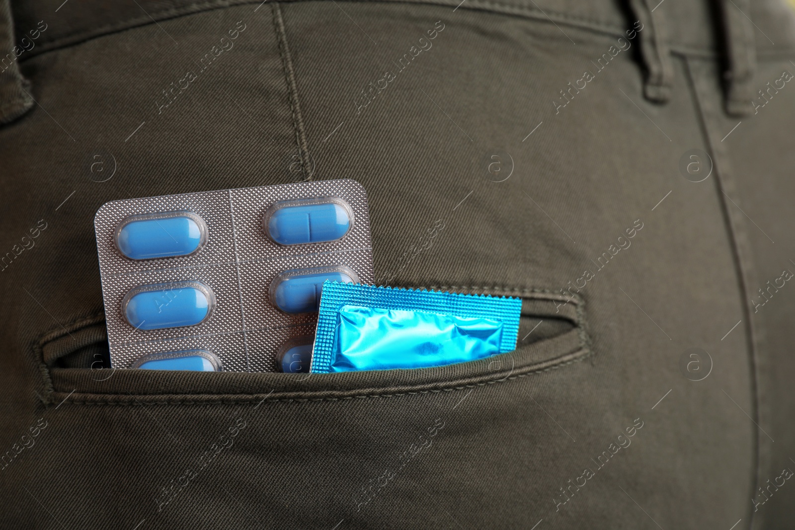 Photo of Jeans with pills and condom in pocket, closeup. Potency problem