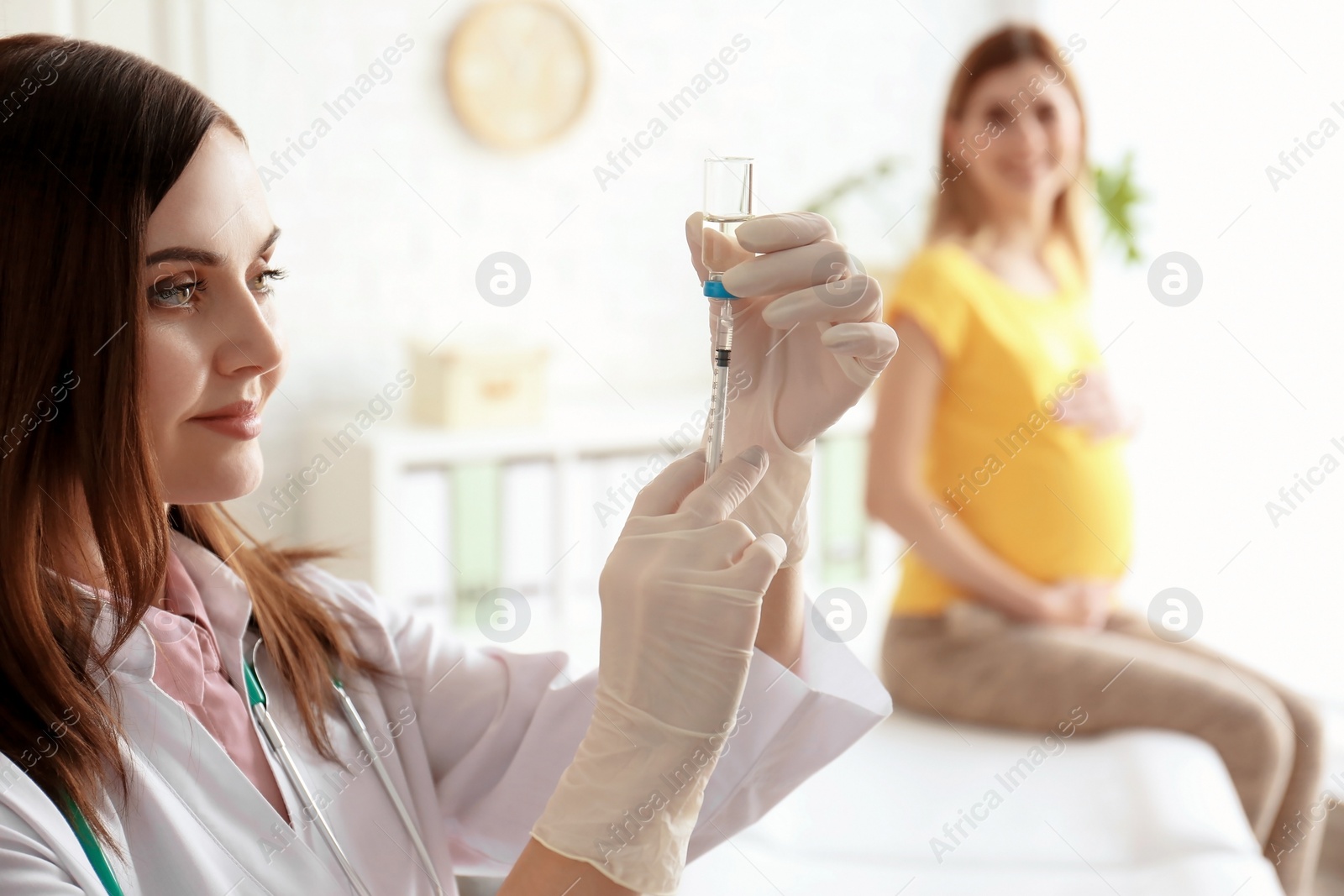 Photo of Doctor holding ampule with vaccine and syringe for patient in clinic