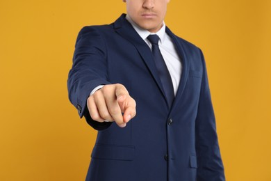 Businessman touching something on yellow background, closeup. Finger gesture