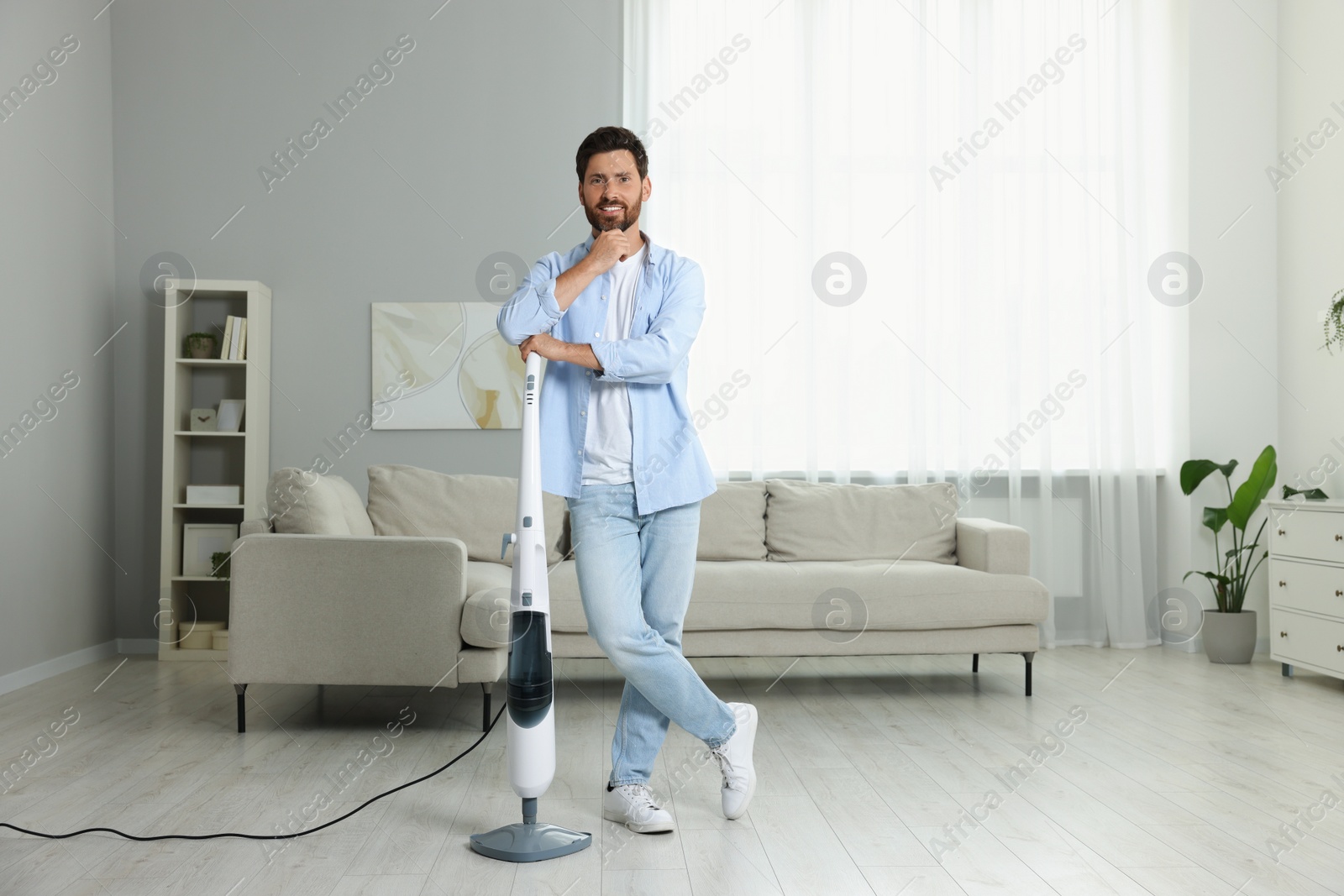 Photo of Happy man with steam mop at home
