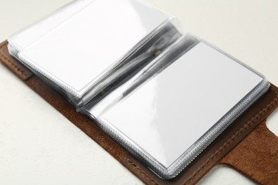 Leather business card holder with blank cards on white table, closeup