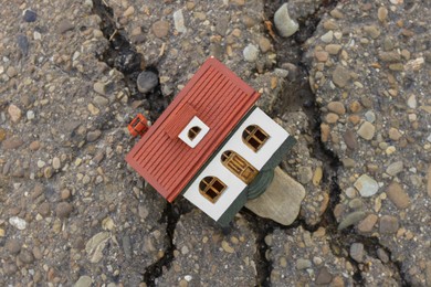 Photo of House model in cracked asphalt, top view. Earthquake disaster