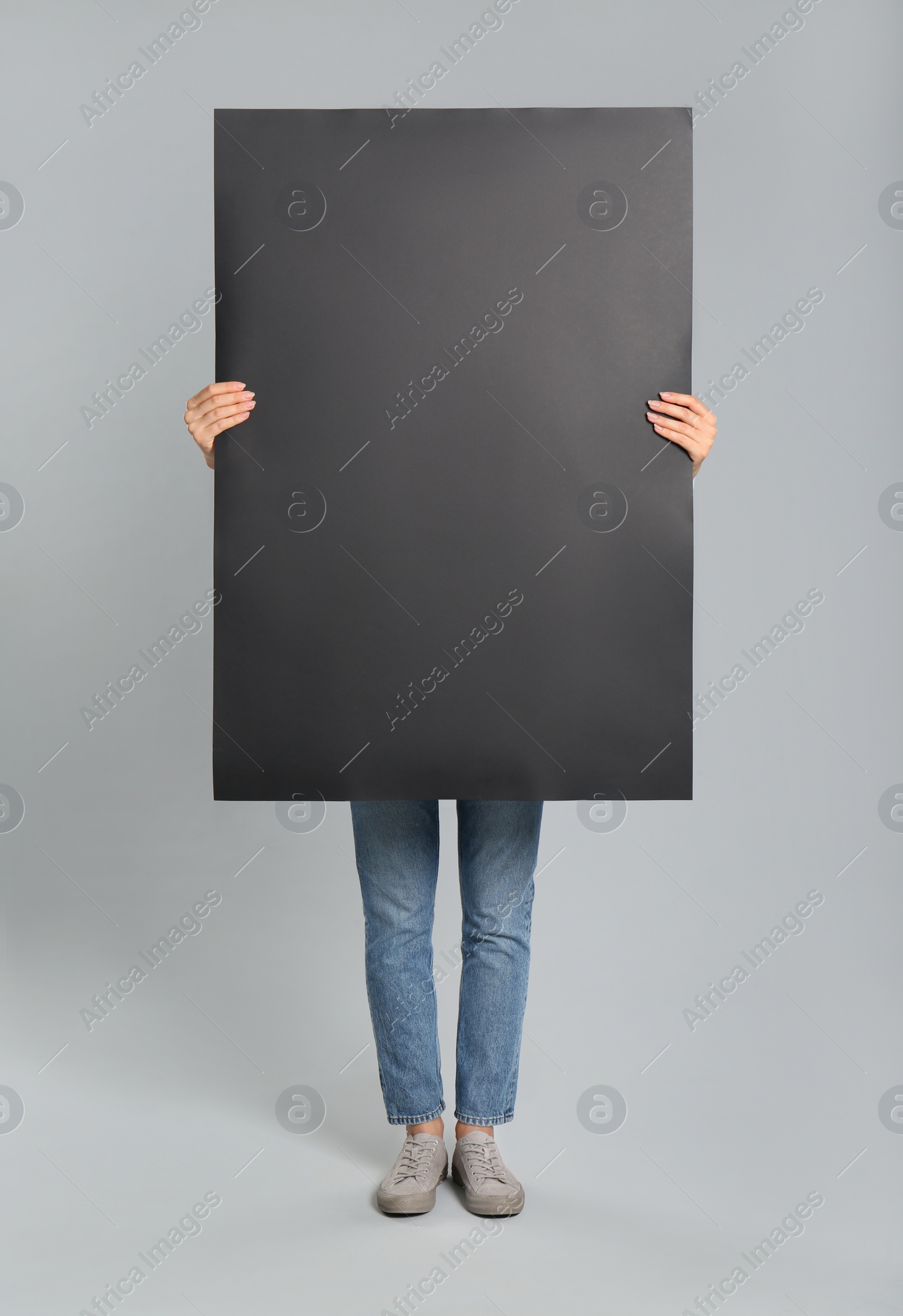 Photo of Woman holding black blank poster on grey background. Mockup for design