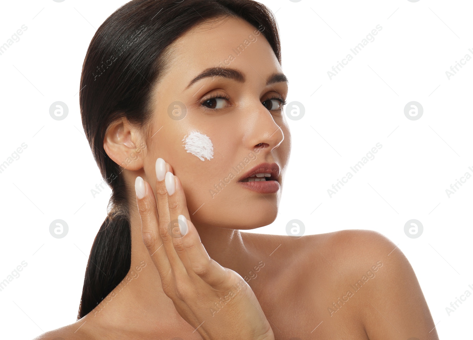 Photo of Young woman applying facial cream on white background