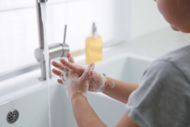 Little girl washing hands with liquid soap at home, closeup