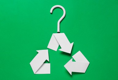 Photo of Recycling symbol in shape of hanger on green background, top view