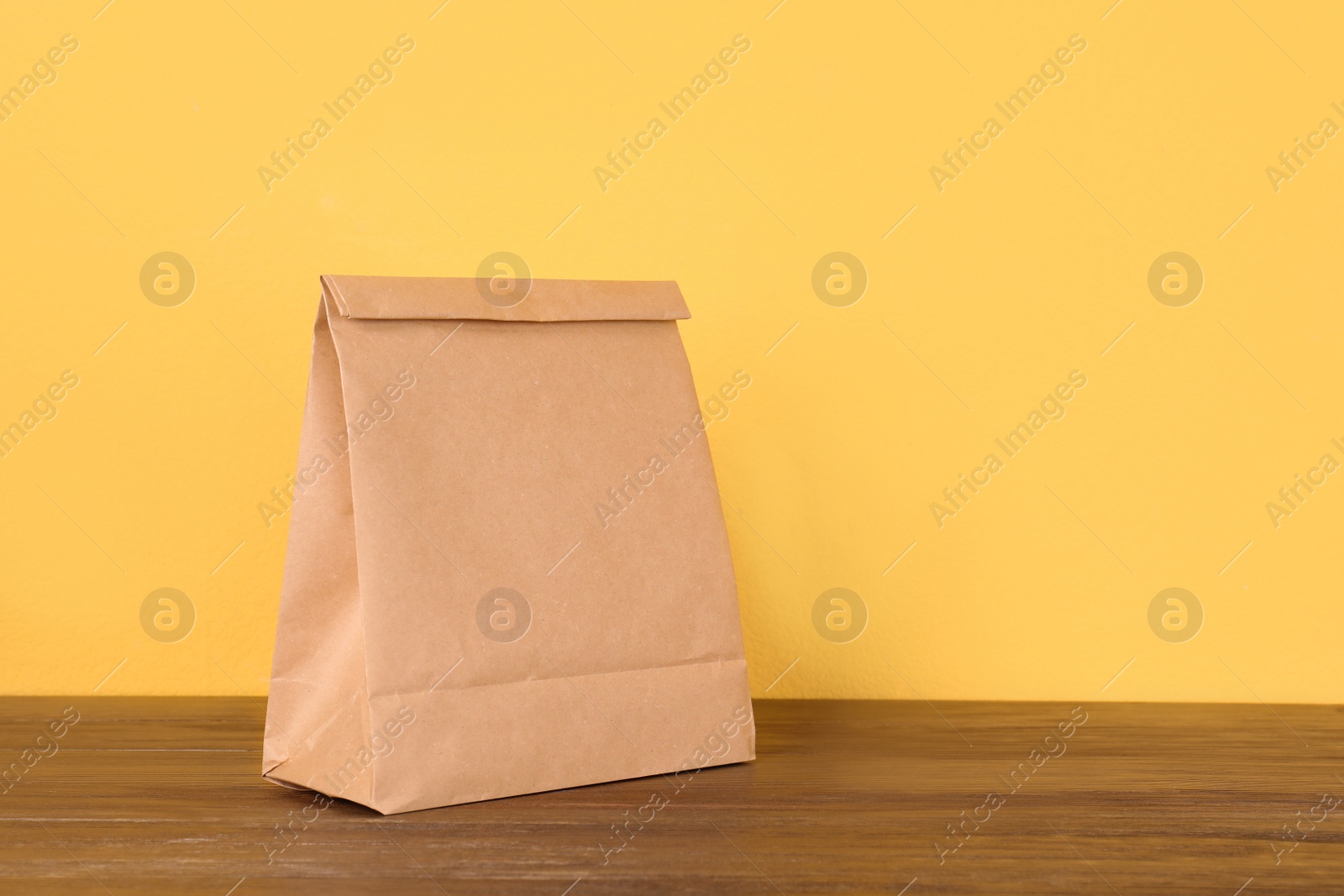 Photo of Paper bag on table against color background. Mockup for design