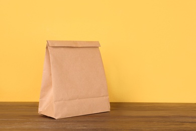 Photo of Paper bag on table against color background. Mockup for design