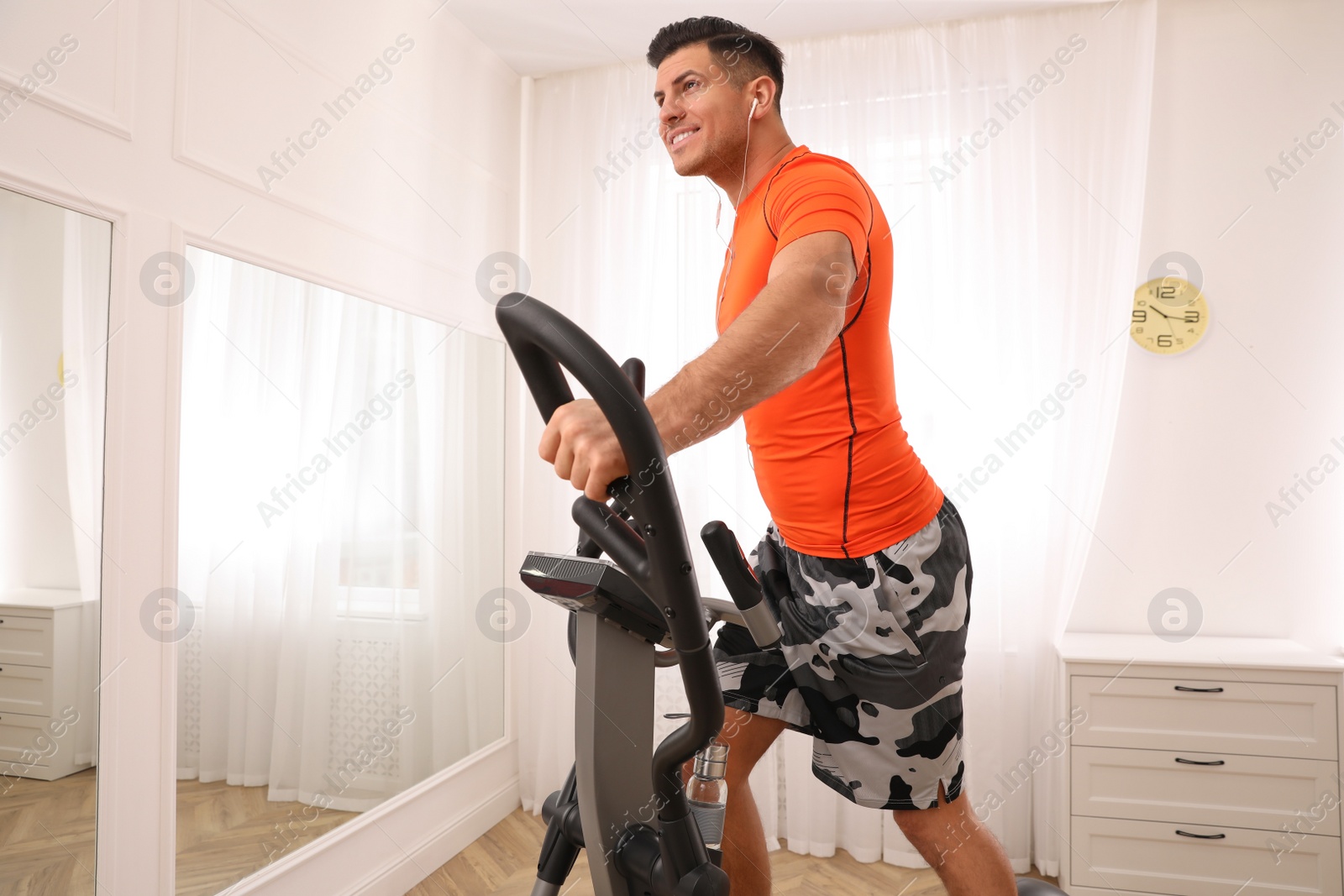 Photo of Man using modern elliptical machine at home