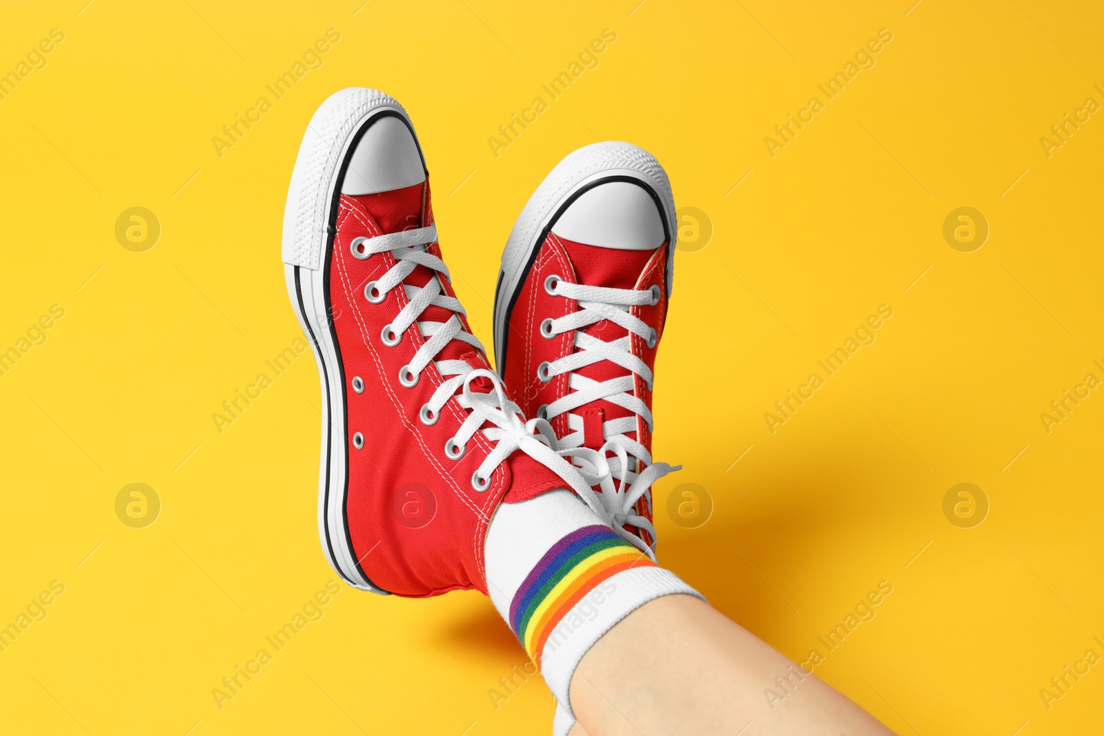 Photo of Woman in stylish gumshoes on yellow background, closeup