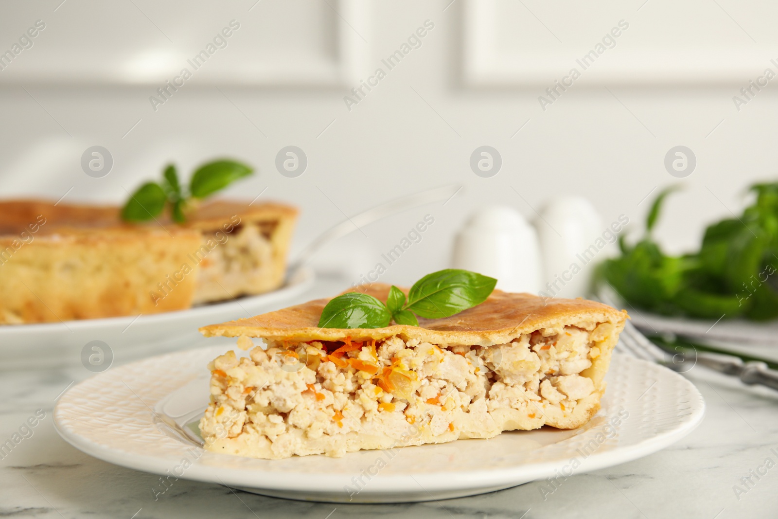 Photo of Piece of delicious pie with meat and basil on white marble table