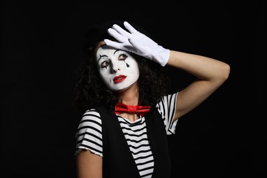 Photo of Young woman in mime costume posing on black background