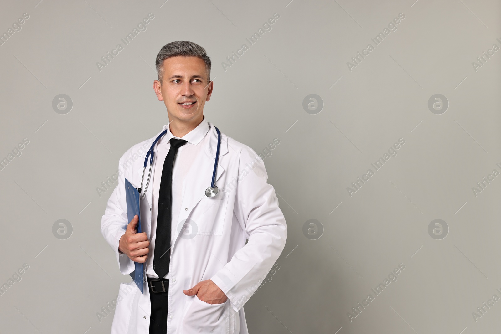 Photo of Doctor with stethoscope and clipboard on grey background, space for text