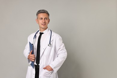 Doctor with stethoscope and clipboard on grey background, space for text