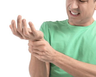 Young man suffering from pain in wrist on white background, closeup