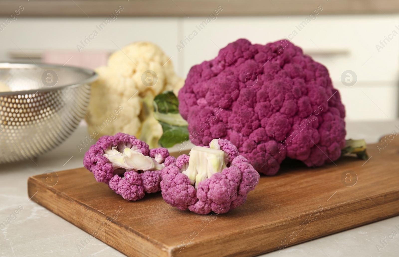 Photo of Wooden board with purple cauliflower cabbage on table. Healthy food