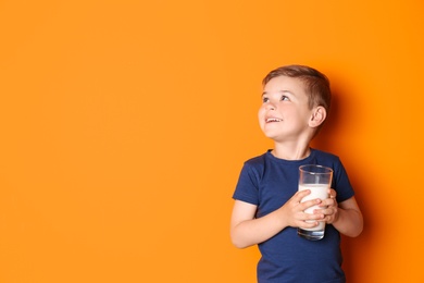 Cute little boy with glass of milk on color background