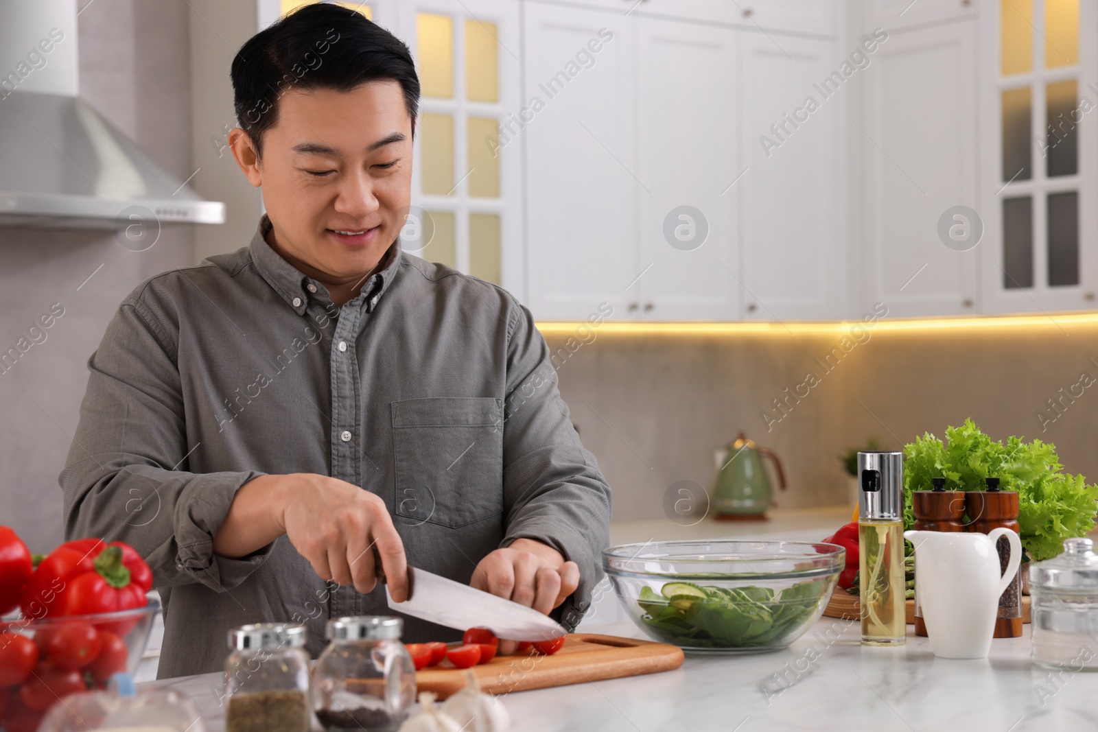 Photo of Cooking process. Man cutting fresh tomatoes at countertop in kitchen