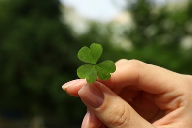 Photo of Woman holding green clover leaf outdoors, closeup