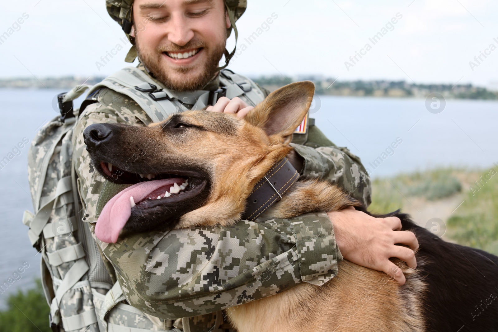 Photo of Man in military uniform with German shepherd dog outdoors