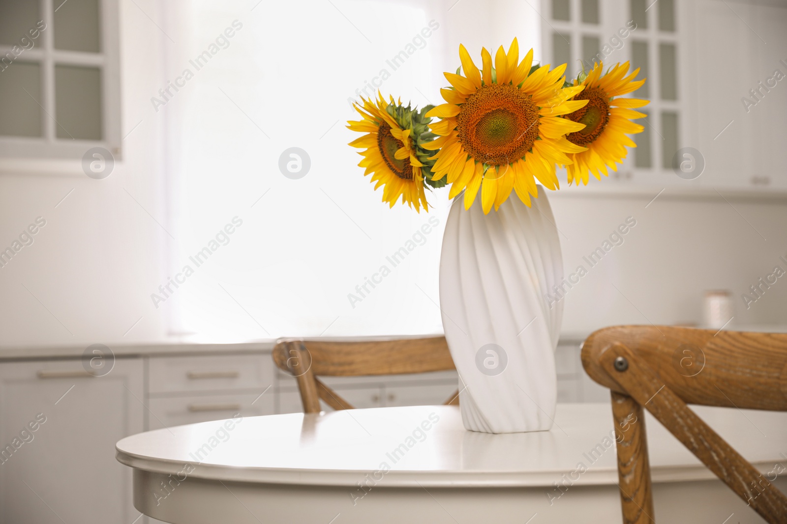 Photo of Bouquet of beautiful sunflowers on table in kitchen