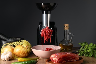 Electric meat grinder with minced beef and products on wooden table