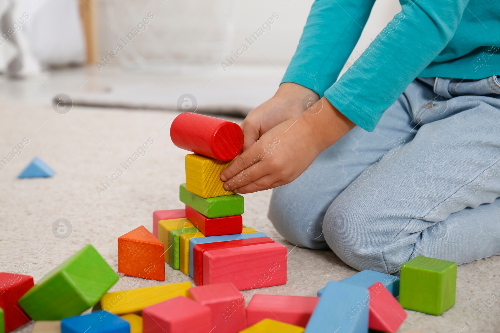 Photo of Cute little girl playing with colorful building blocks at home, closeup